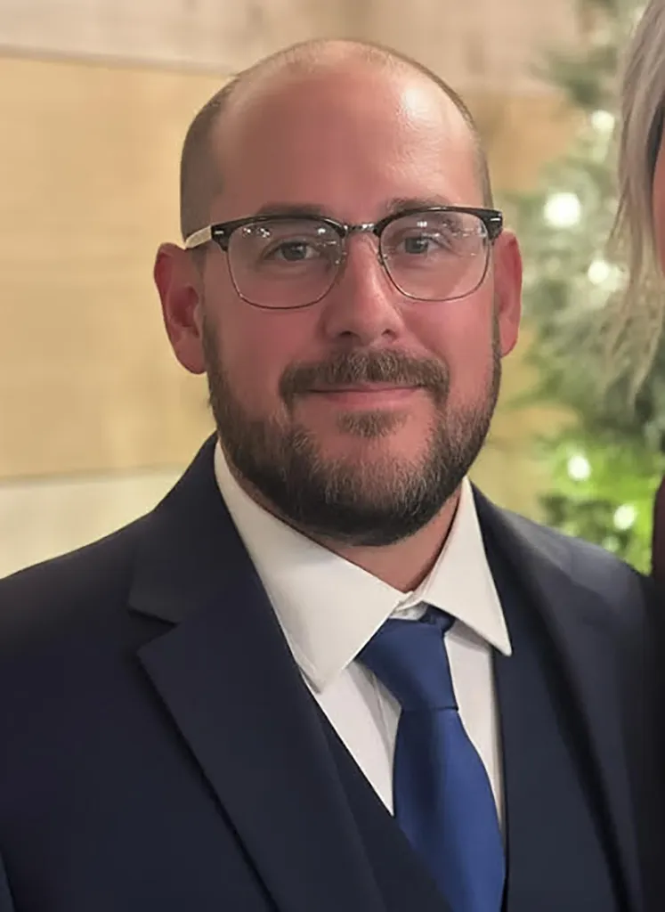 Michael Muhlebeck in a blue suit with a blue tie.