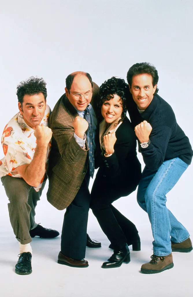 From left, Michael Richards, Jason Alexander, Julia Louis-Dreyfus, and Jerry Seinfeld from Seinfeld smiling at the camera with their fists clenched.