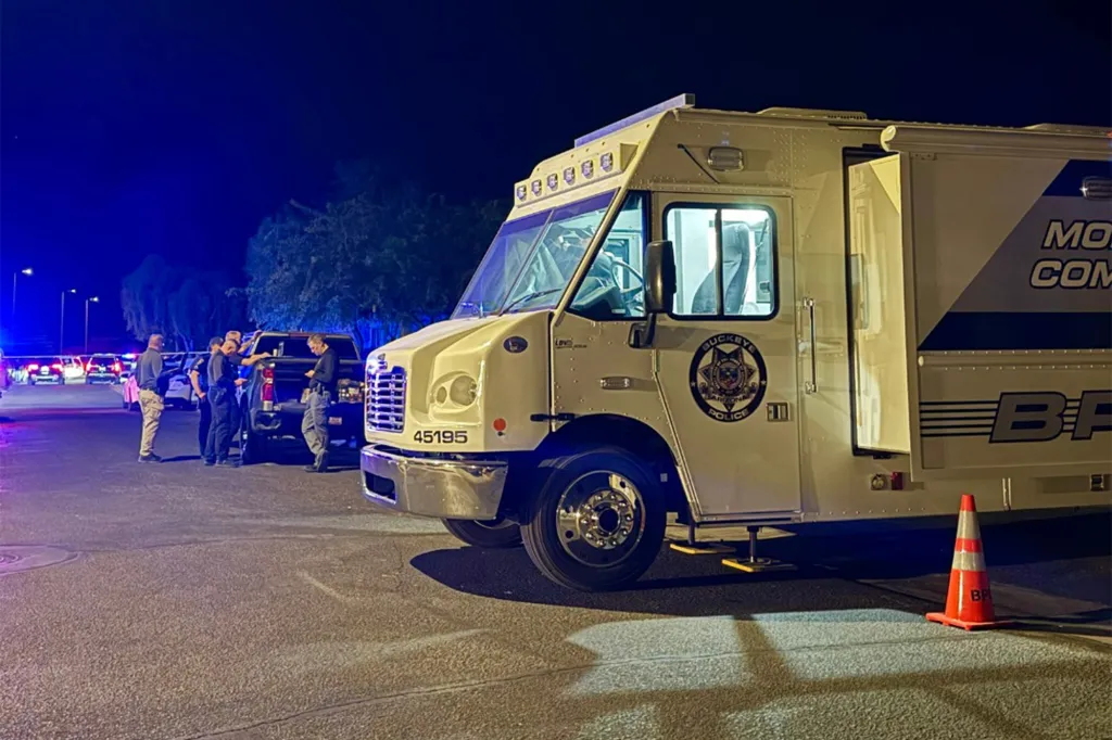 Police officers and vehicles at a crime scene at night.