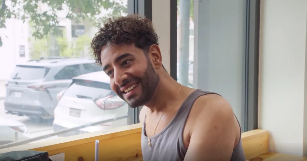 Mido smiles while wearing a gray tank top and a gold chain.