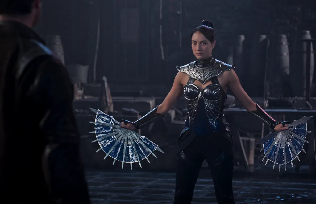 Adeline Rudolph as Kitana in armored attire holds two bladed fans in a scene from Mortal Kombat II.