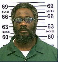 Mugshot of David McClary, a Black man with glasses and a beard, in a green uniform.