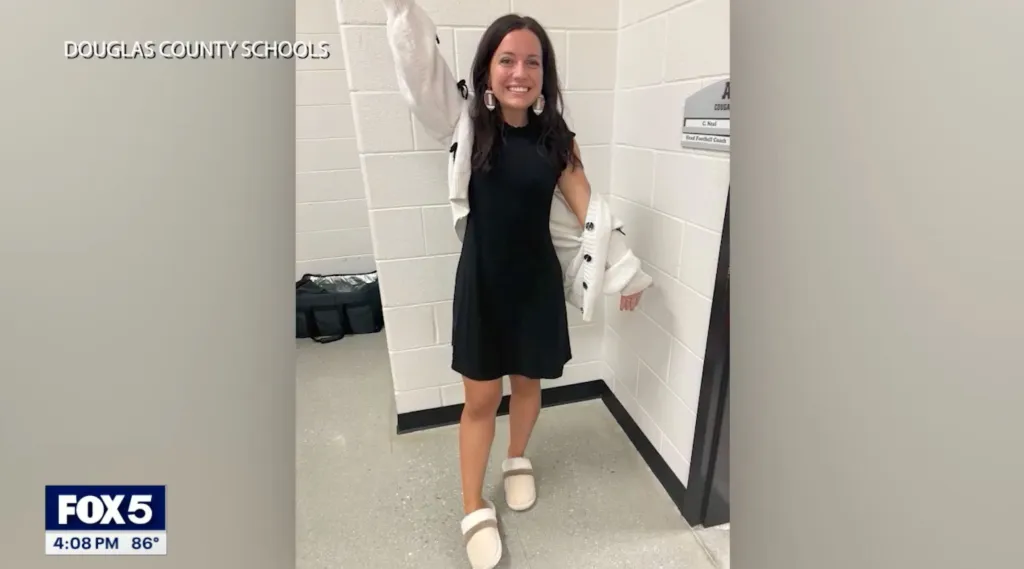 Maris Nichols, a former teacher and coach, smiling in a school hallway.