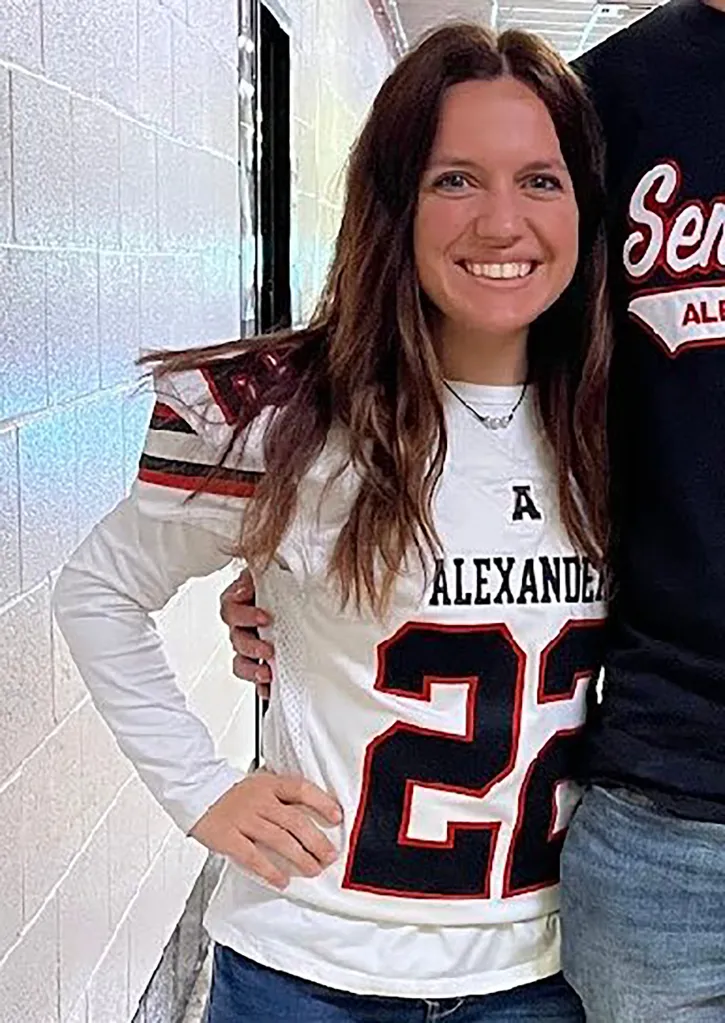 Maris Nichols, a former Alexander High School teacher, wearing a white sports jersey with