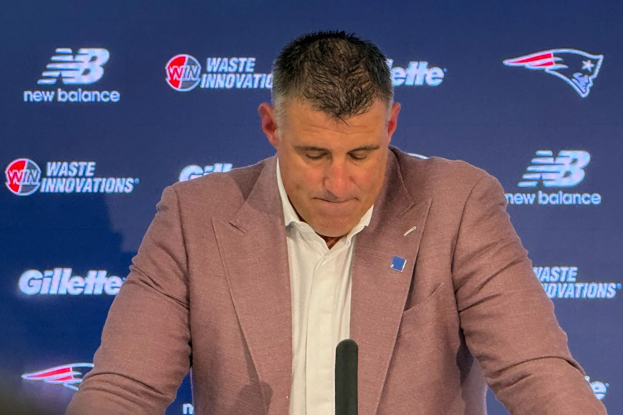 New England Patriots coach Mike Vrabel looking down at a press conference.
