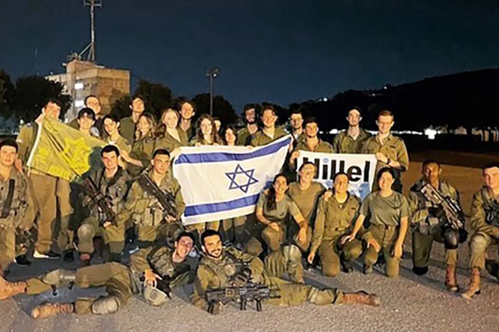 A group of young people in military uniforms holding Israeli and Hillel flags.