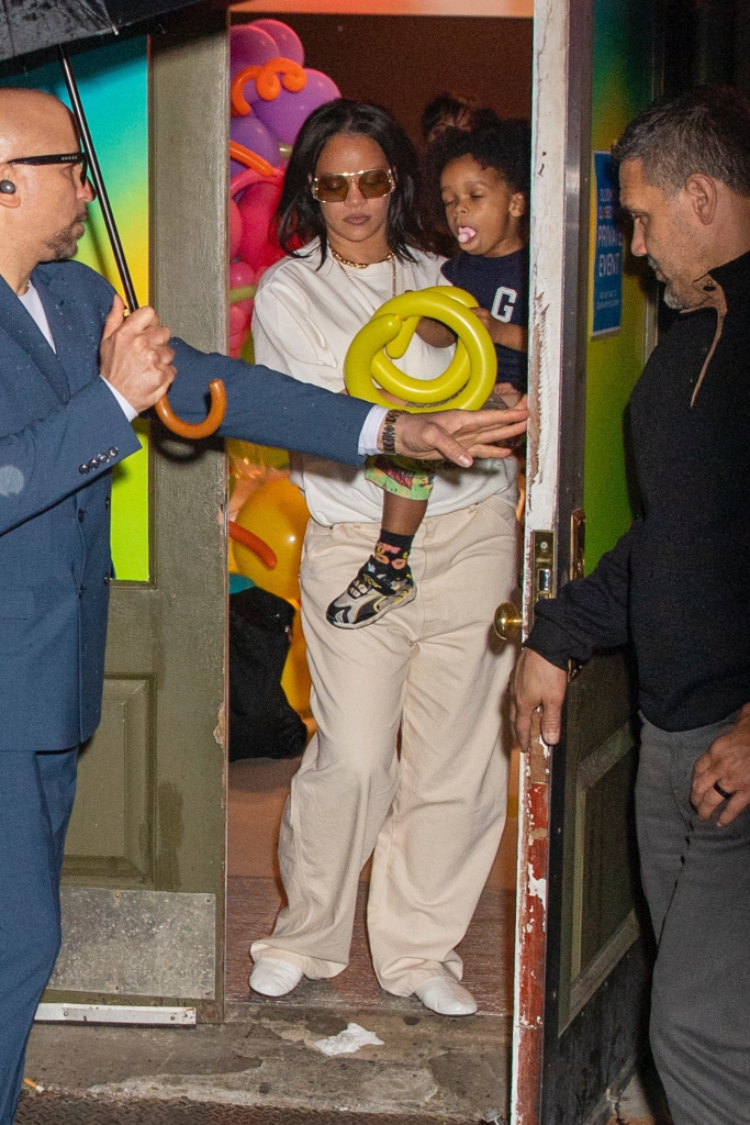 Rihanna holding RZA as he plays with a yellow balloon animal.