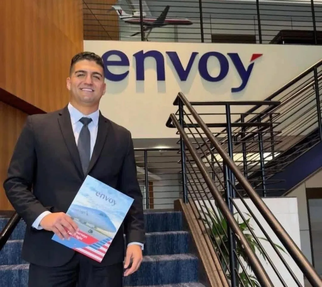 Ramzi, a newly graduated flight instructor, smiling while holding an Envoy brochure.
