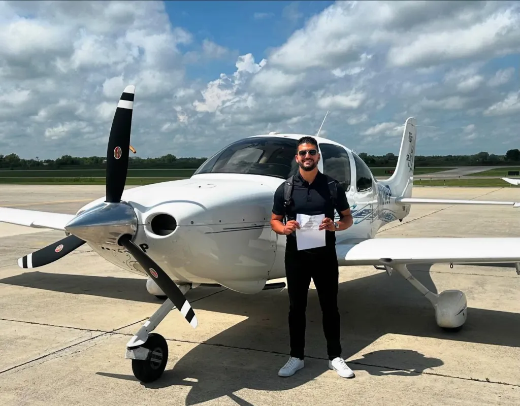 Ramzi, a flight instructor, standing in front of a white propeller plane.