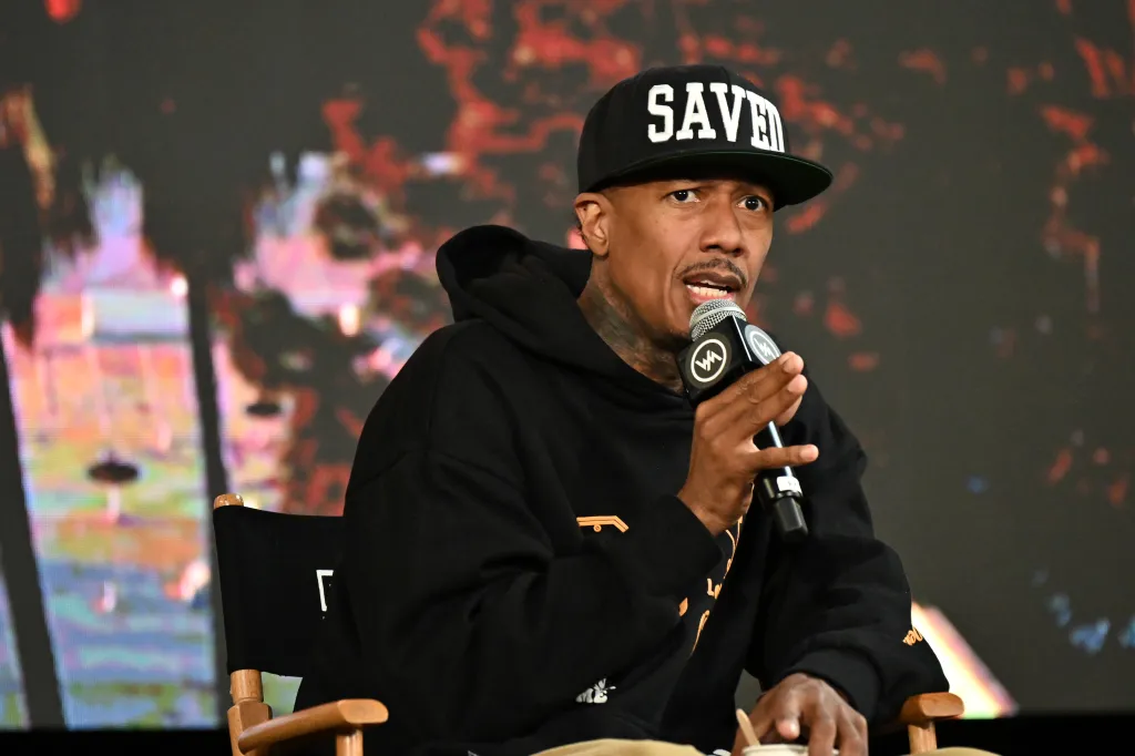Nick Cannon speaking into a microphone while wearing a 