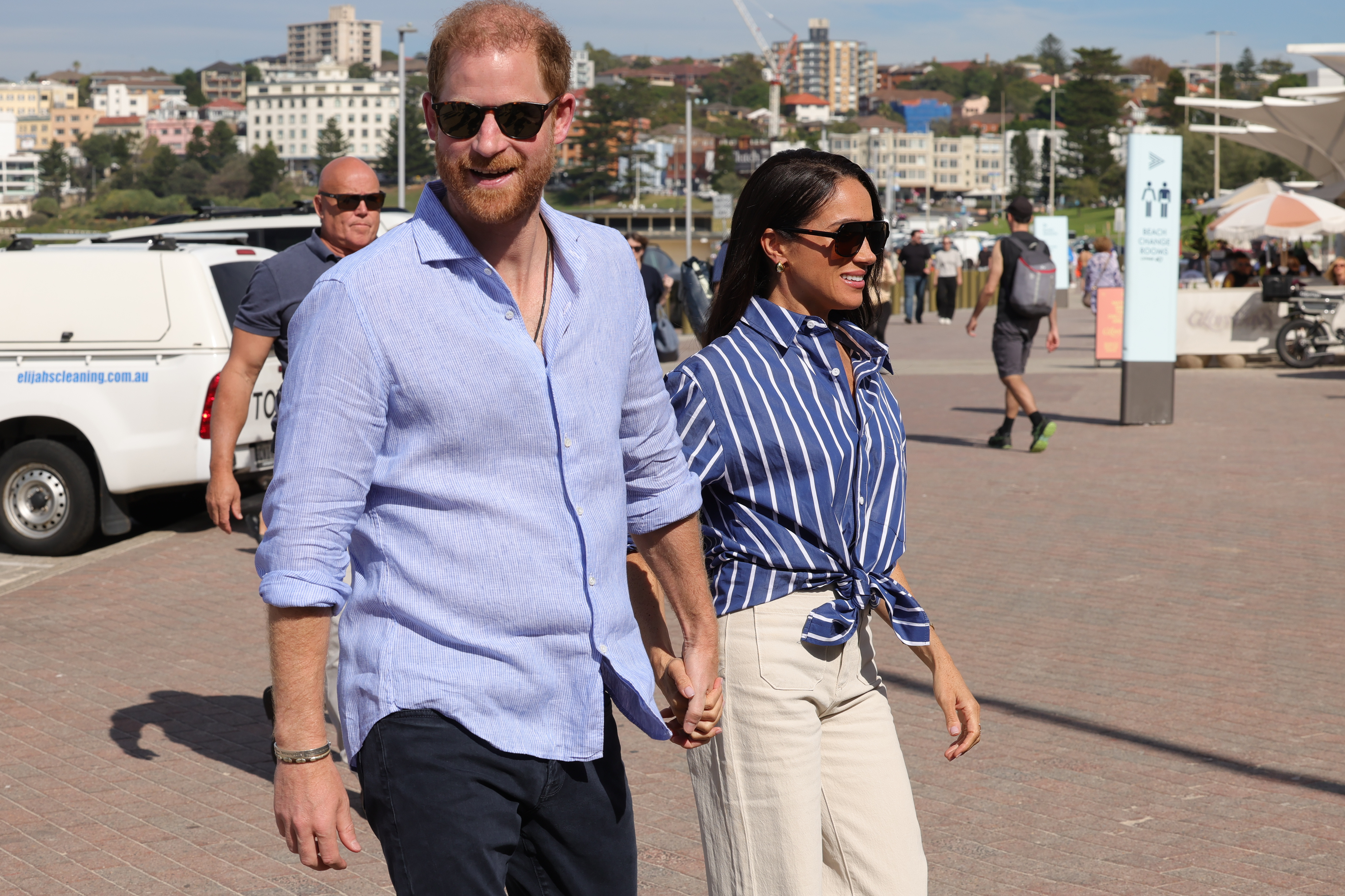 Prince Harry and Meghan Markle holding hands at Bondi Beach in Sydney.
