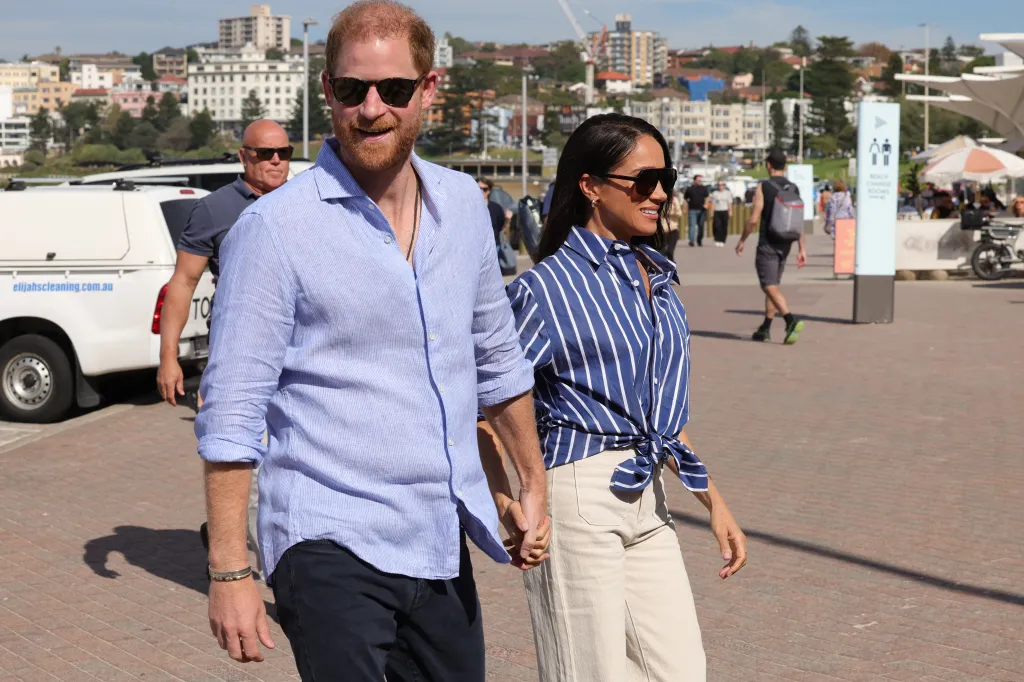Prince Harry and Meghan Markle holding hands at Bondi Beach.