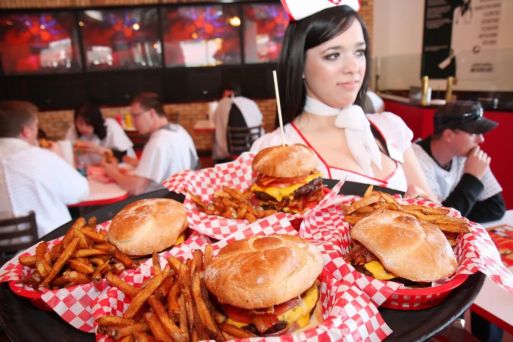 Nurse Yenny holding a tray of burgers and fries at the Heart Attack Grill.
