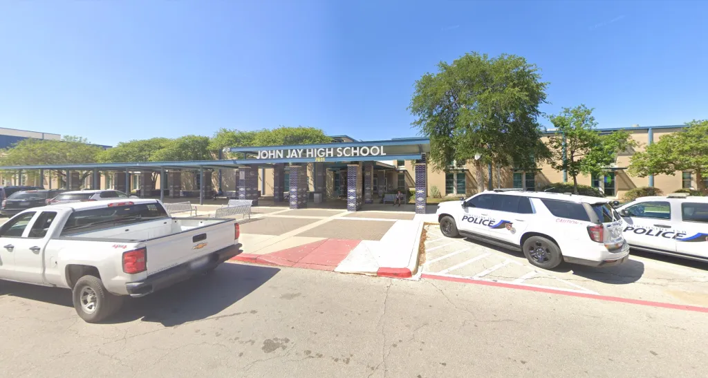 The exterior of John Jay High School with two Northside ISD police vehicles parked in the foreground.
