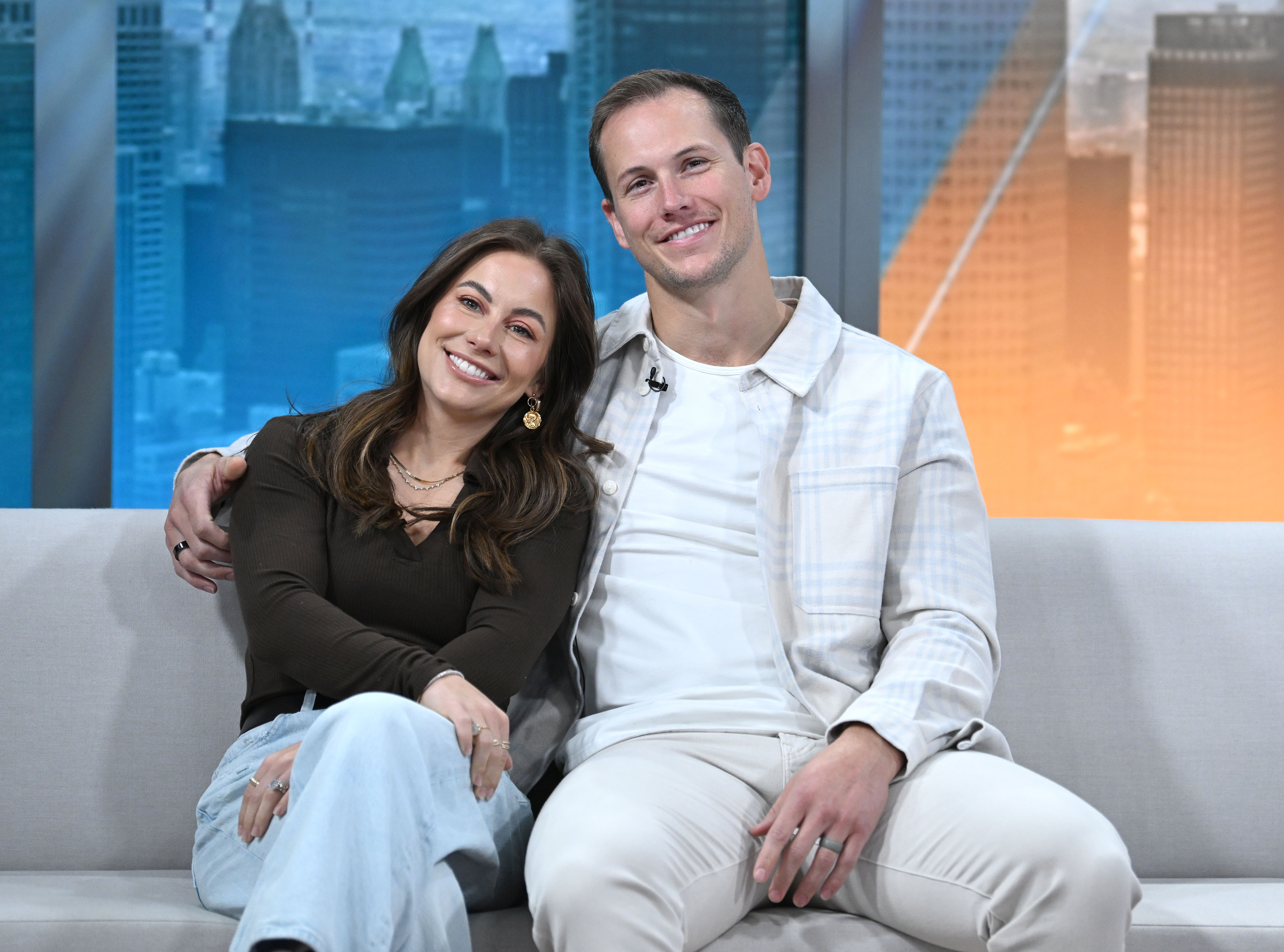 Shawn Johnson East and Andrew East posing together on a couch.