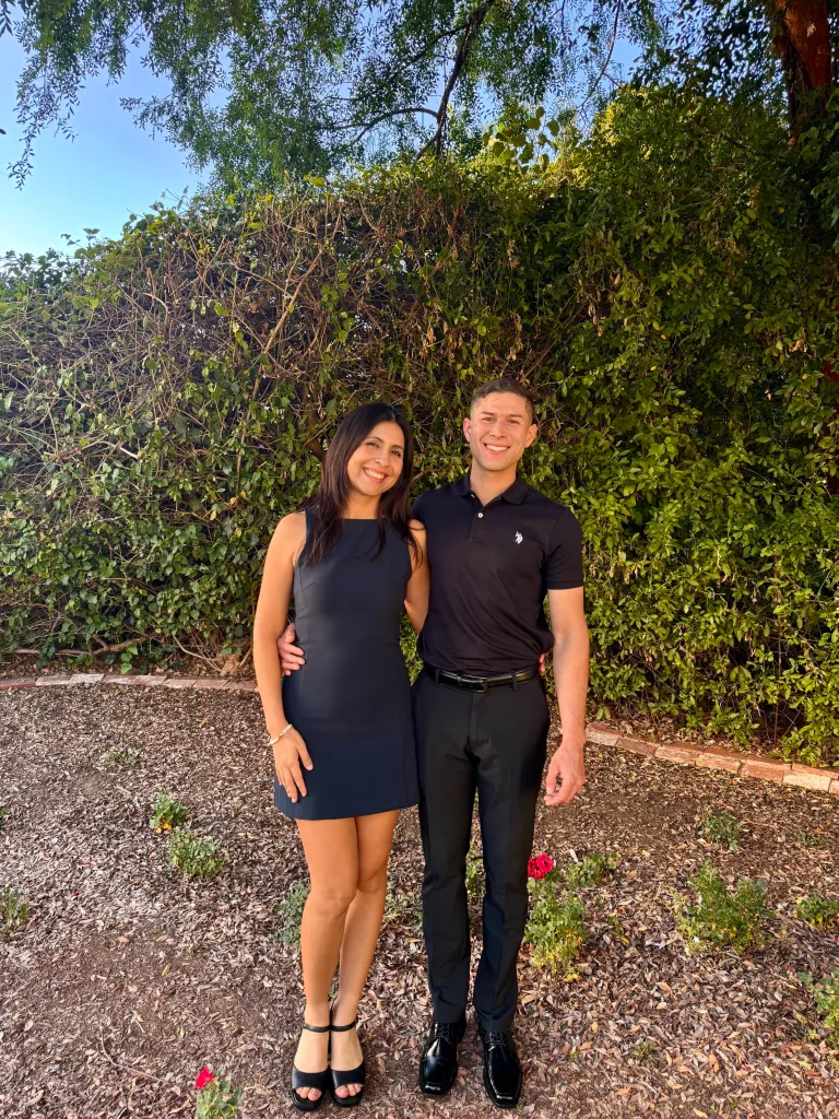 Shaina Montiel, a hantavirus survivor, poses with her boyfriend in front of a leafy green hedge.