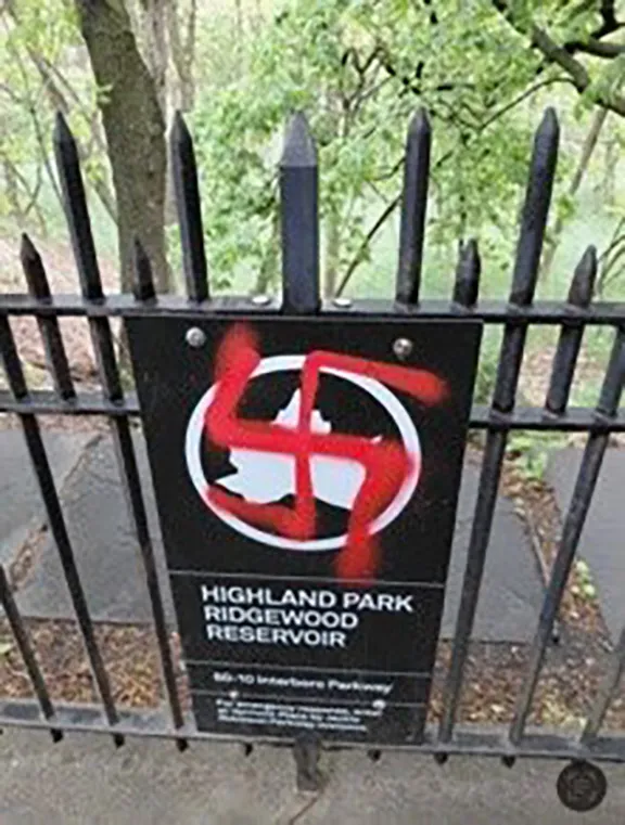 A red swastika spray-painted over a sign for Highland Park Ridgewood Reservoir.