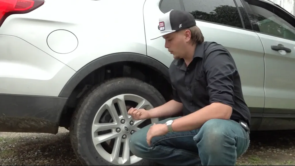 Anderson crouches down to look at a tire of his car after the vehicle's brakes went out on May 15, 2026.