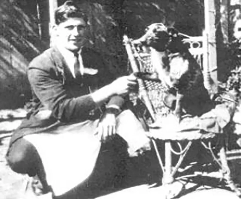 Black and white photo of a man and a dog on a chair.