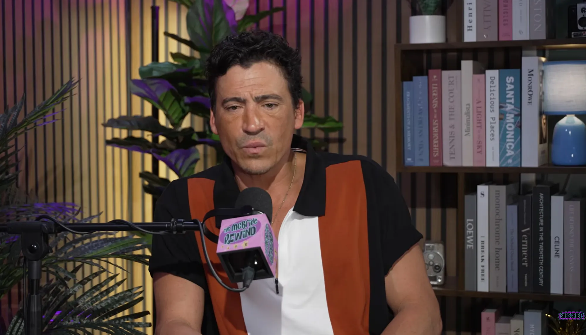An actor wearing a collared shirt on a podcast set, discussing residual checks.