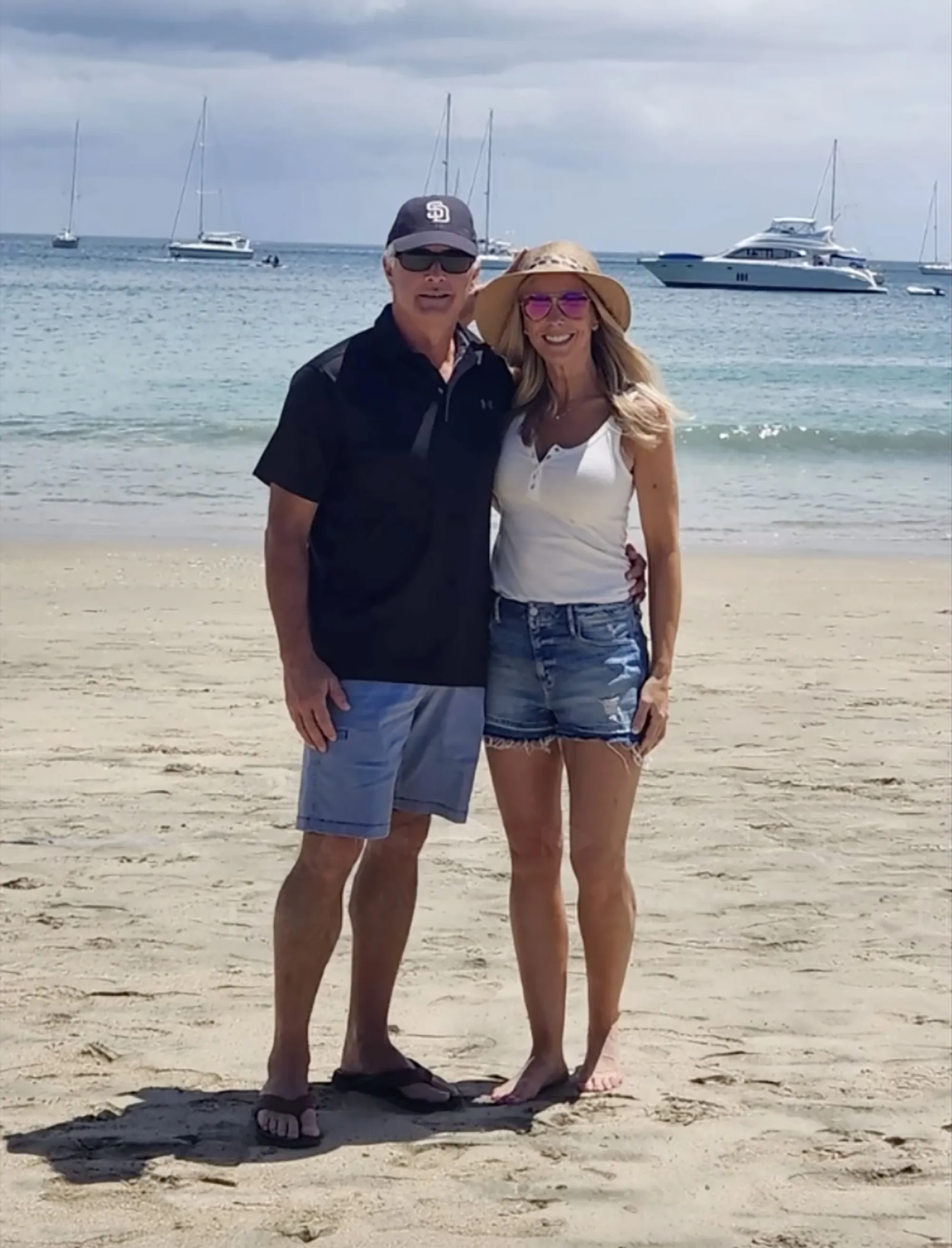 Kate Gosselin and Steve Neild smiling on a beach with boats in the background.