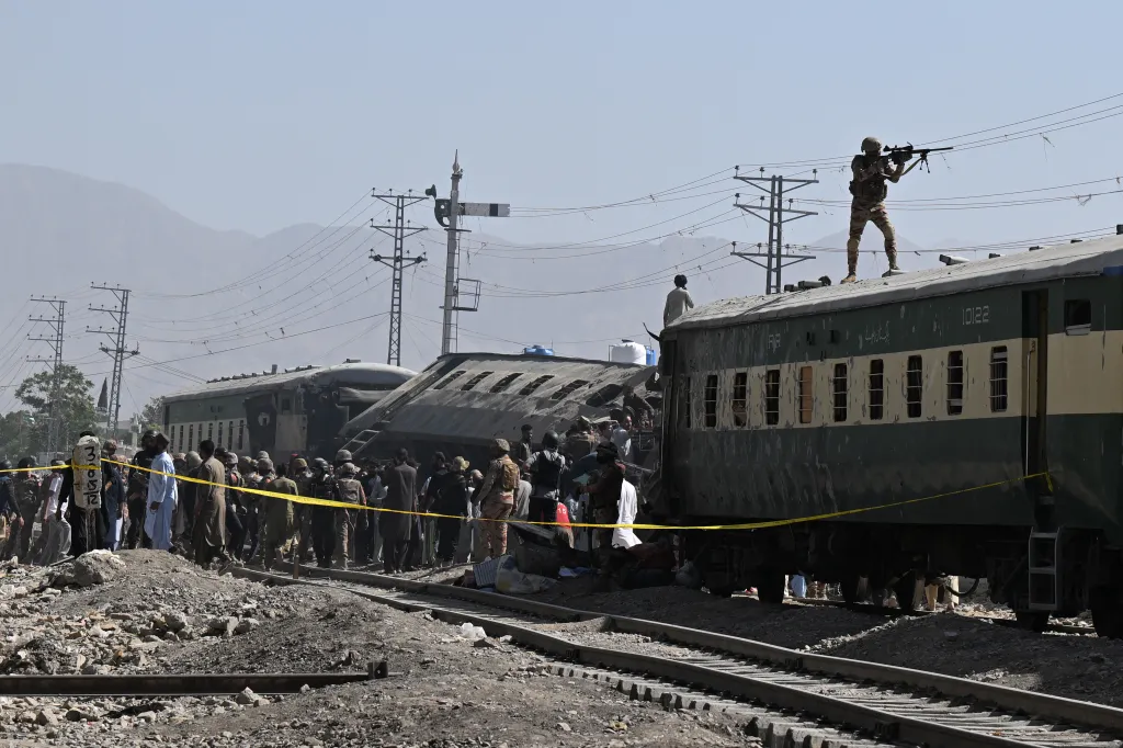 A Pakistani soldier aims his weapon from atop a carriage as security officials inspect derailed train carriages after an explosion targeted a train in Quetta on May 24, 2026.