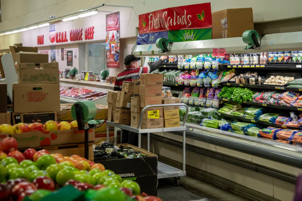 An employee stocking shelves in the produce section of a grocery store.