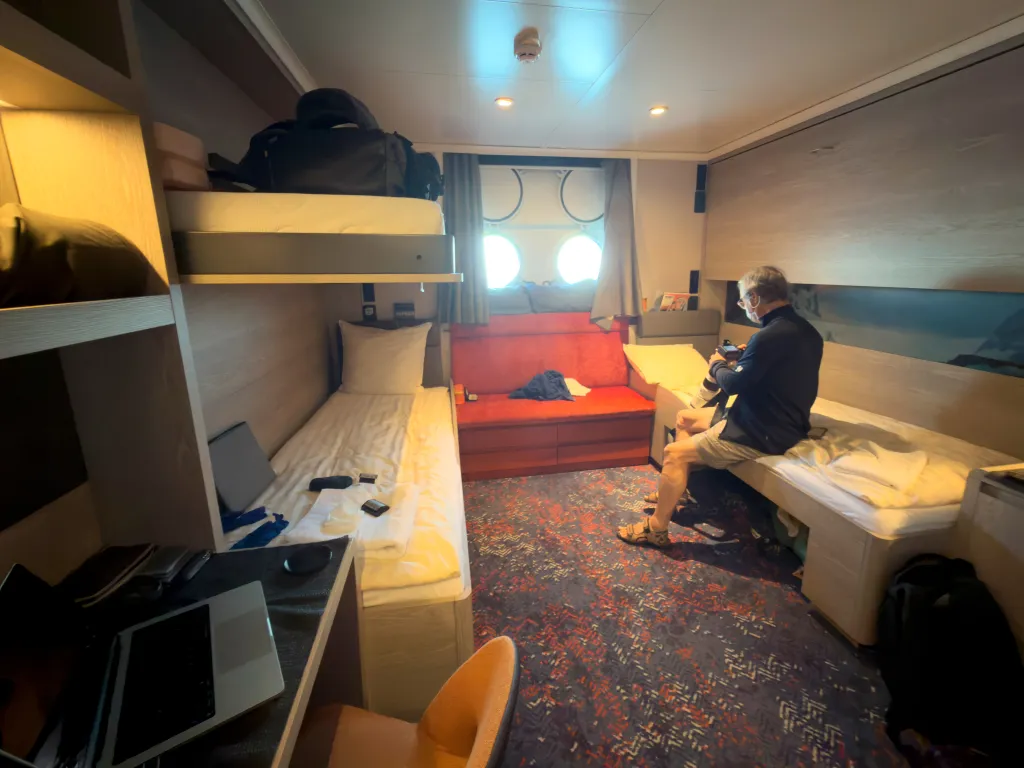 A passenger wearing a face mask checks his camera in a cabin on the Hantavirus-stricken cruise ship MV Hondius.