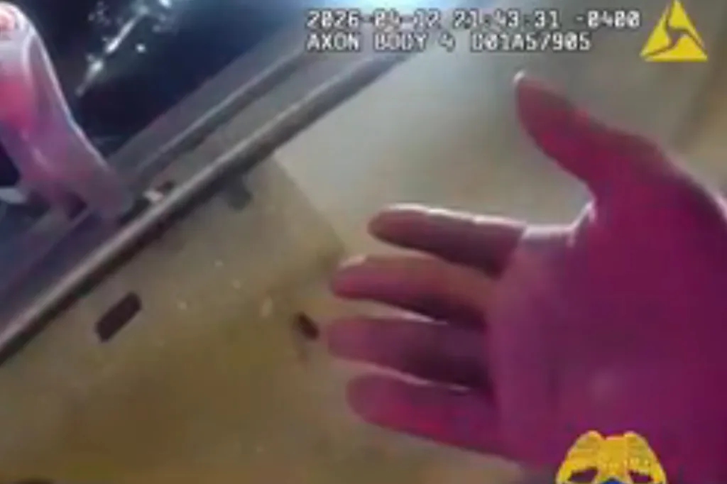 A still from a bodycam showing an officer's hand reaching towards a man on the edge of a bridge.