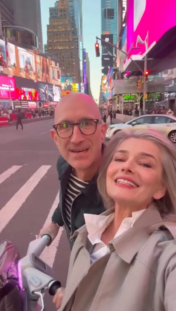 Paulina Porizkova and Jeff Greenstein smiling at the camera in Times Square.