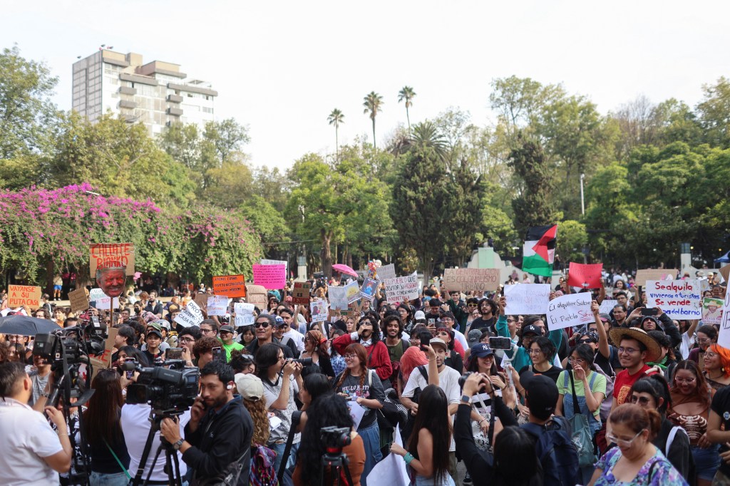 A large crowd of people holding protest signs and Palestinian flags.