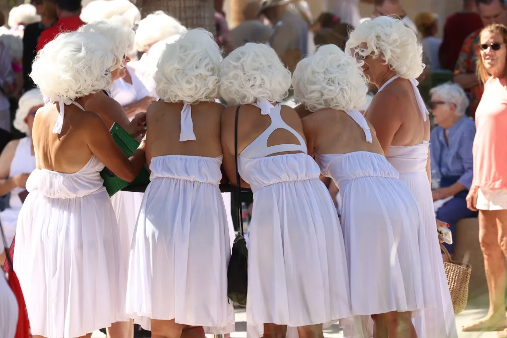 Group of people in white dresses and blonde wigs gathered for a Marilyn Monroe look-alike world record attempt.