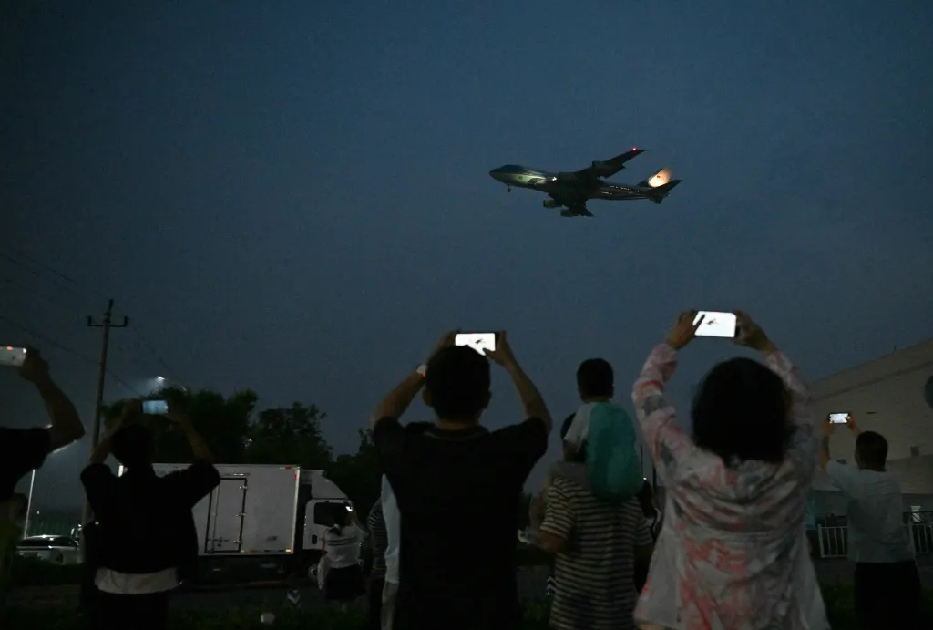 People film Air Force One arriving at Beijing Capital Airport at dusk.