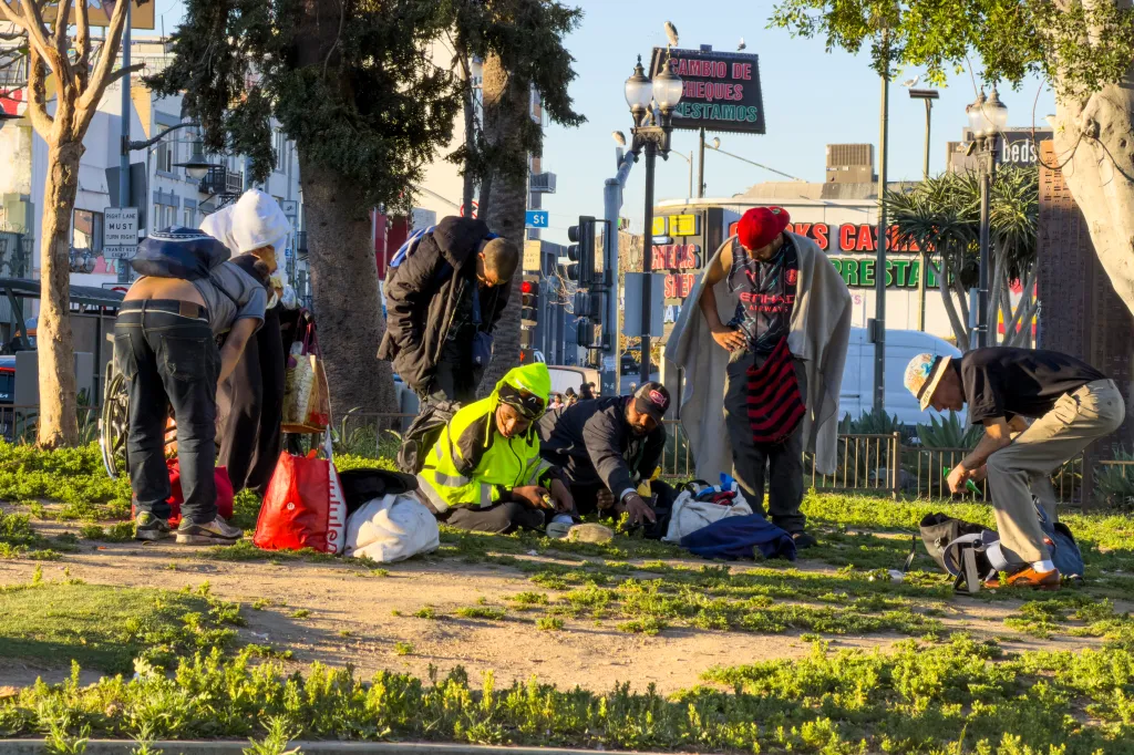People huddle while smoking at MacArthur Park in Los Angeles.