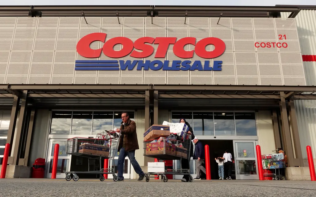 People leaving a Costco Wholesale store with full shopping carts.
