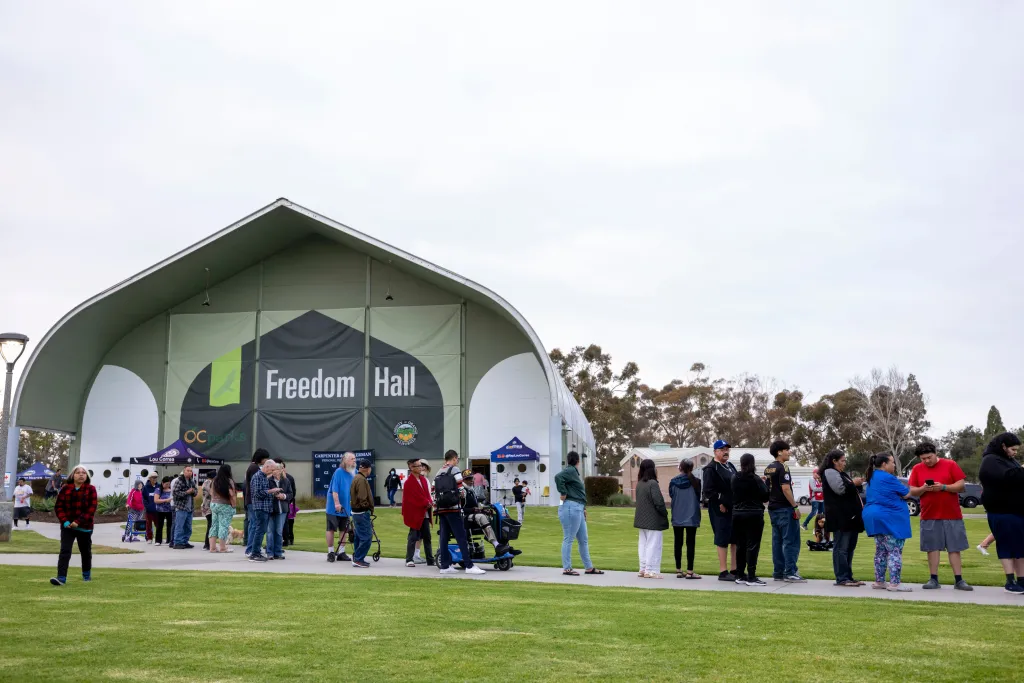 People line up for dinner outside Freedom Hall, where an evacuation center is set up, at Mile Square Regional Park in Fountain Valley, California.