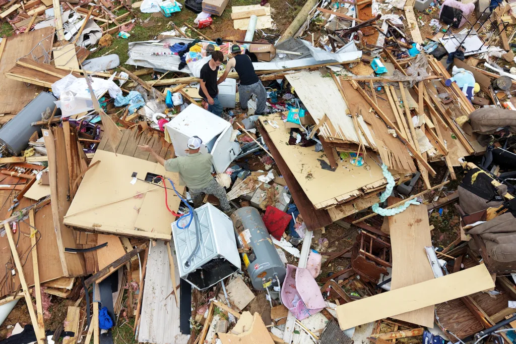 Three men move debris in a trailer park following a tornado.