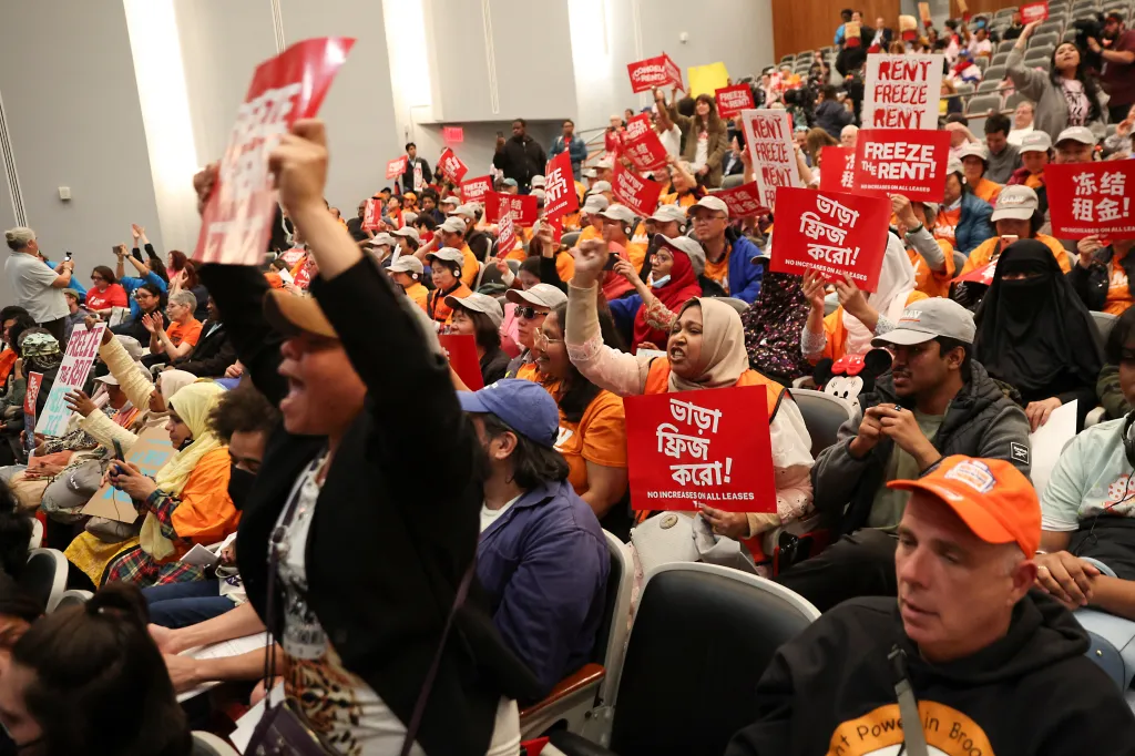 People at a public hearing hold signs that say 