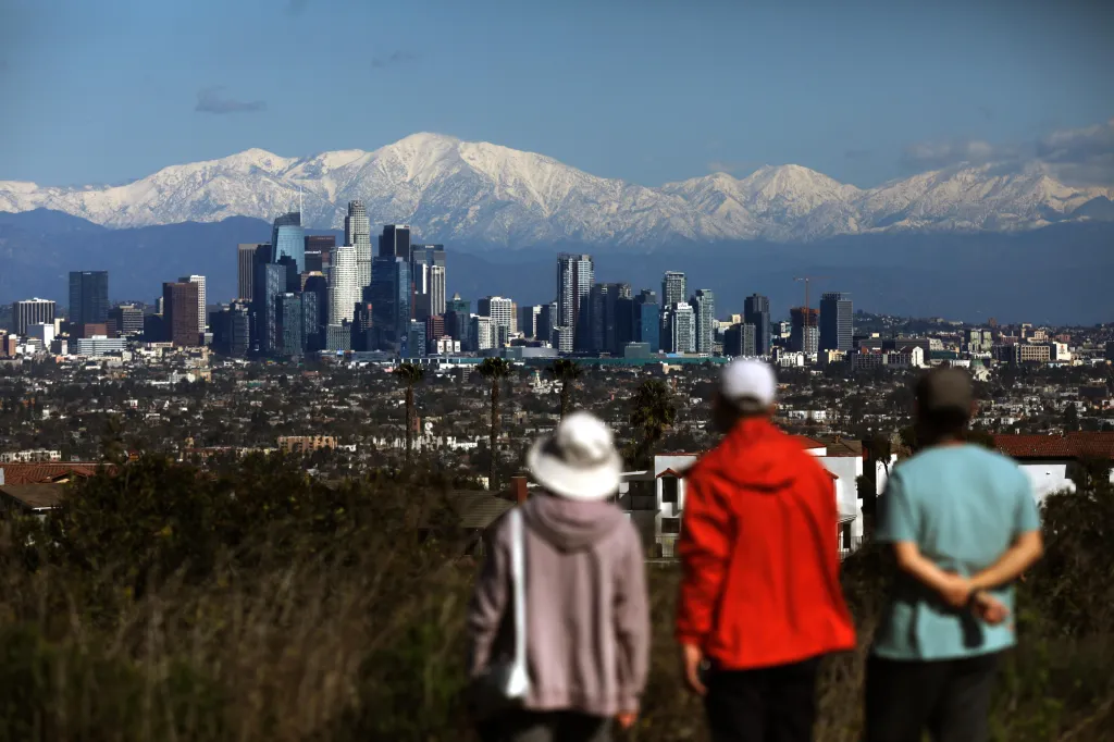People view the Los Angeles skyline and snow-capped San Gabriel mountains from Kenneth Hahn State Recreation Area.