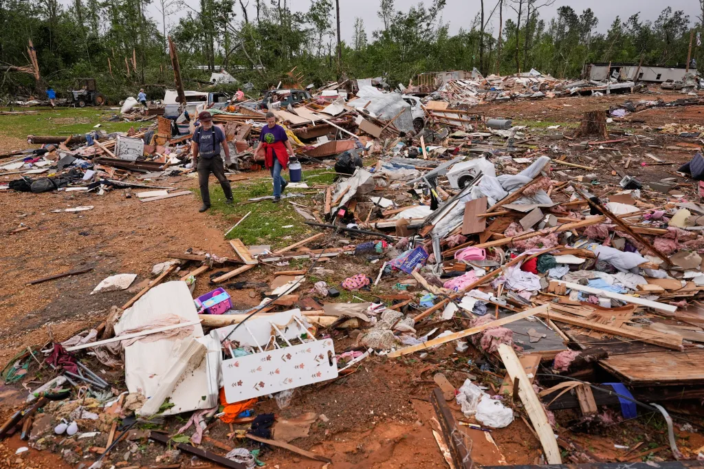 Two people walk through the debris of a mobile home park destroyed by a tornado in Bogue Chitto, Mississippi.