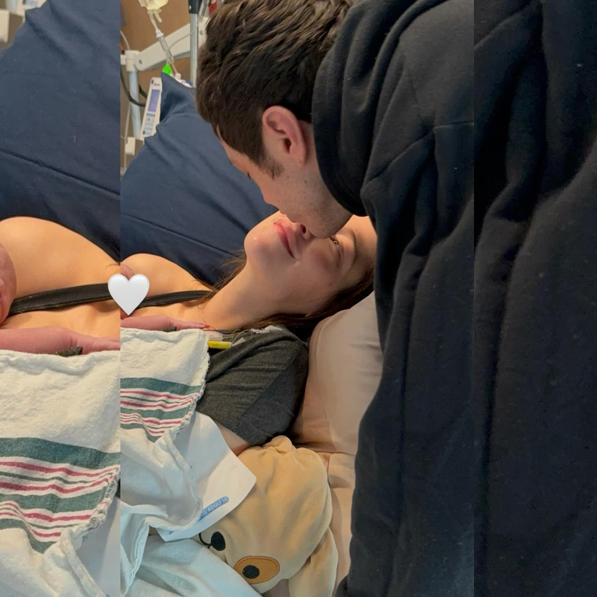 A man kissing a woman on the forehead as she holds a newborn in a hospital bed.