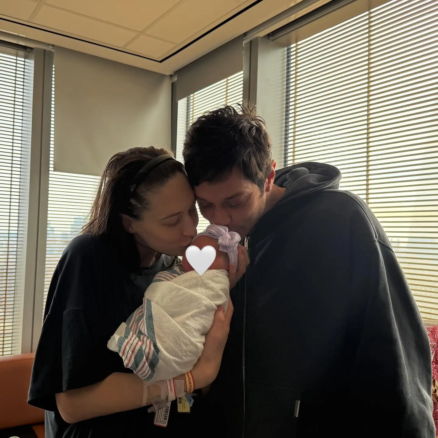 Pete Davidson and Elsie holding and kissing a newborn baby.