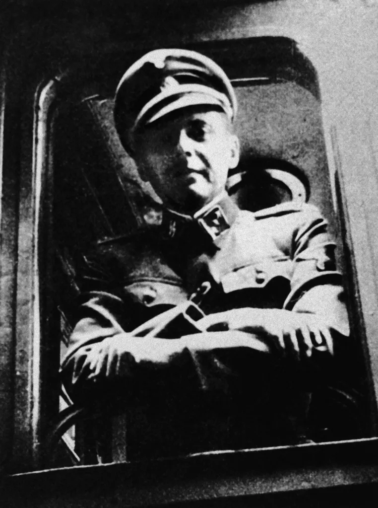 Josef Mengele in SS uniform standing at a train window.