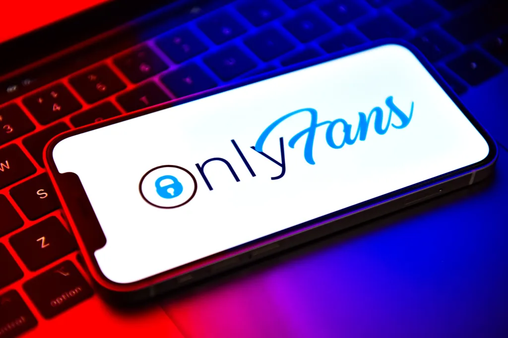 Illustration of the OnlyFans logo displayed on a smartphone screen, resting on a keyboard.