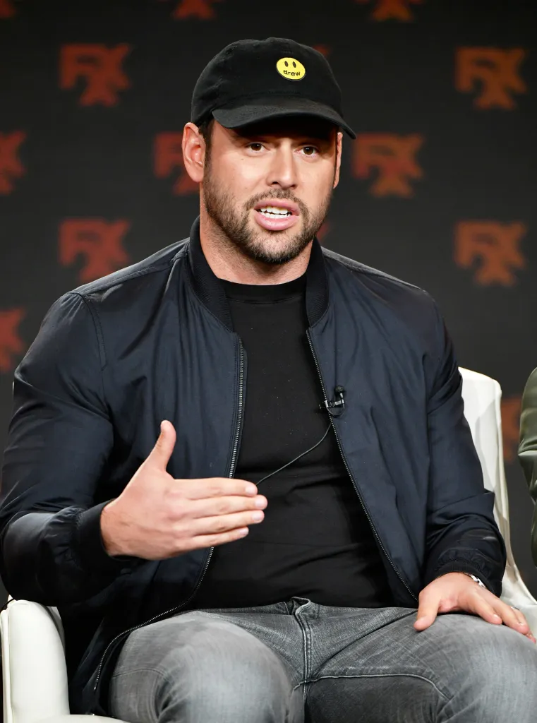 Scooter Braun wearing a black baseball cap with a yellow smiley face logo.