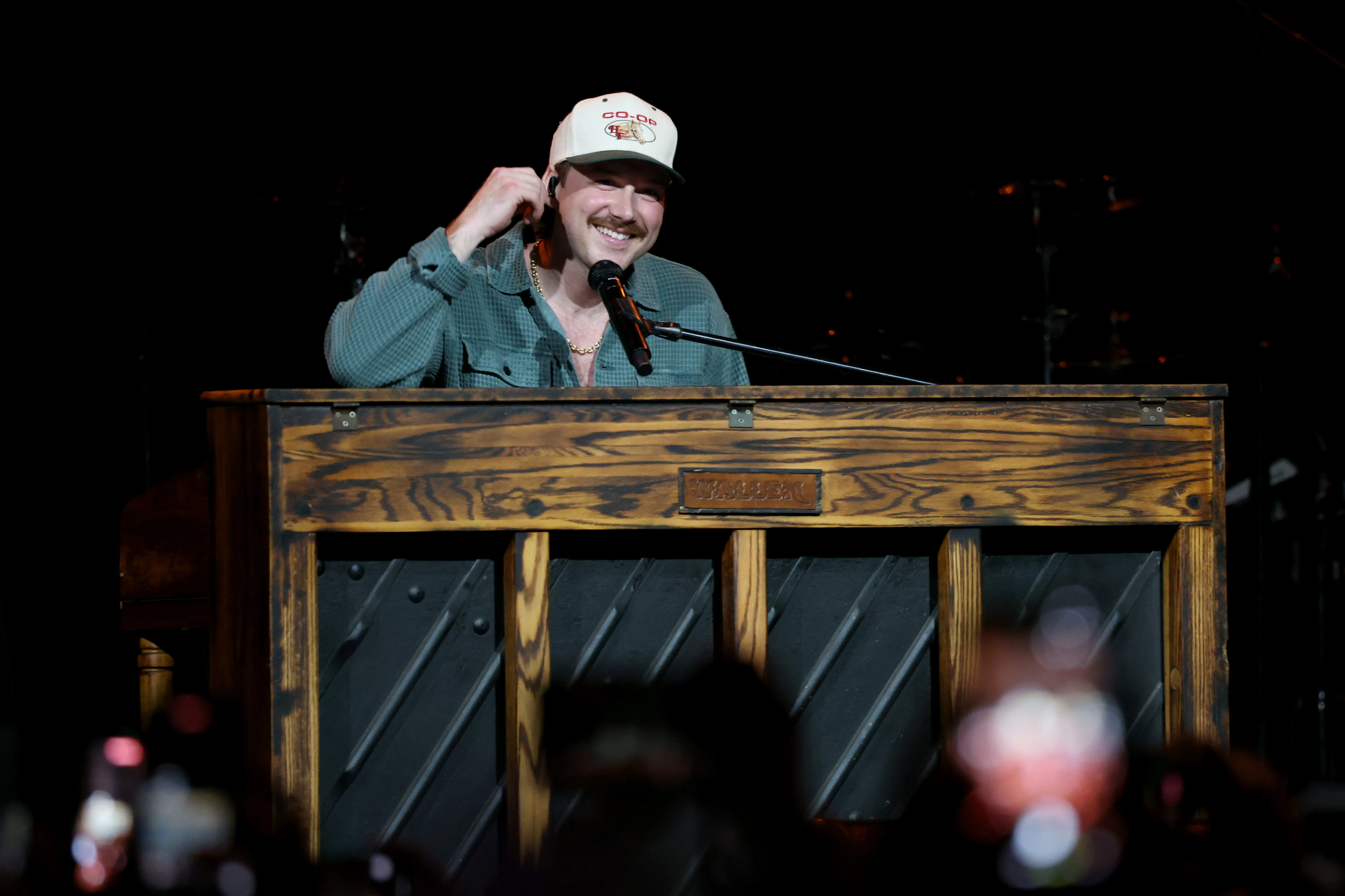 Morgan Wallen smiles while performing at a piano.