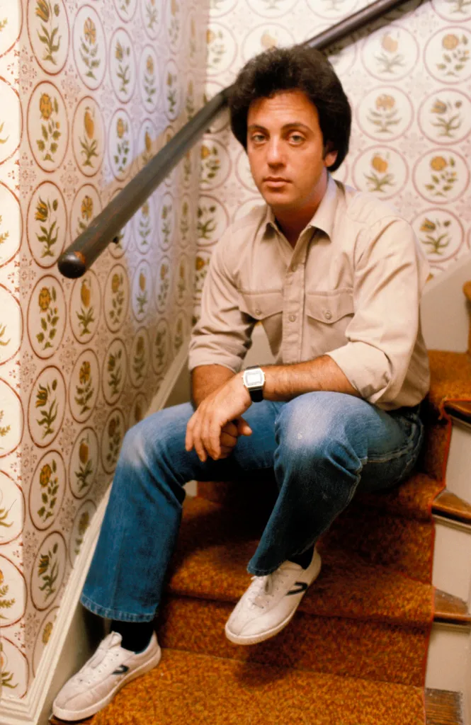 Billy Joel sitting on carpeted stairs.