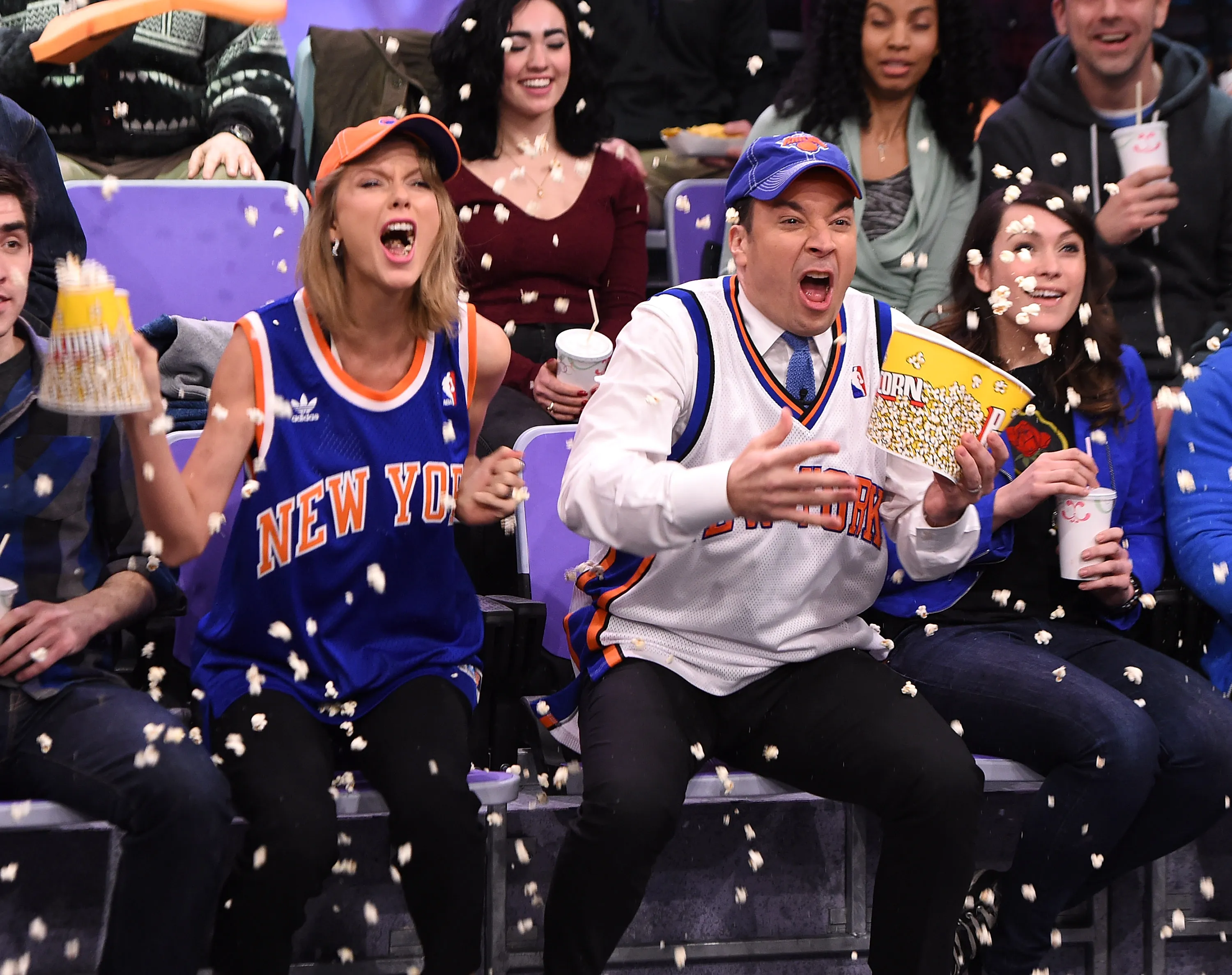 Taylor Swift and Jimmy Fallon yell as popcorn flies in the air around them.