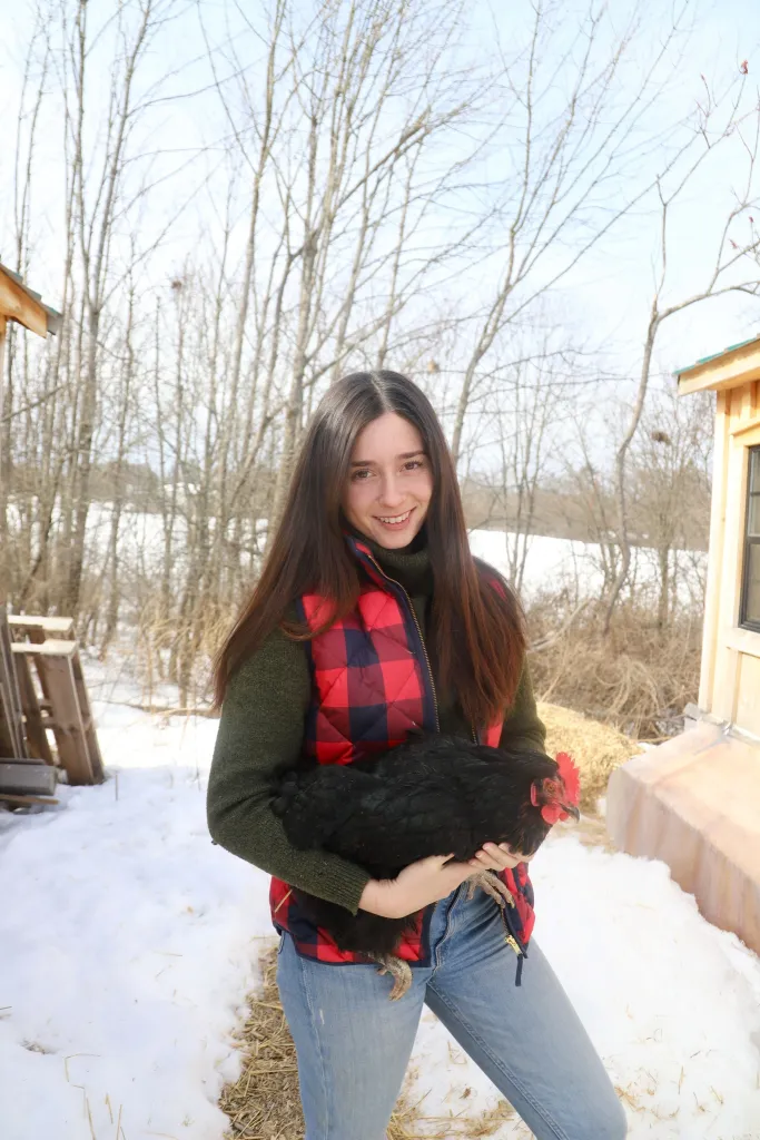Alexandra Fasulo holding a black chicken with red comb.