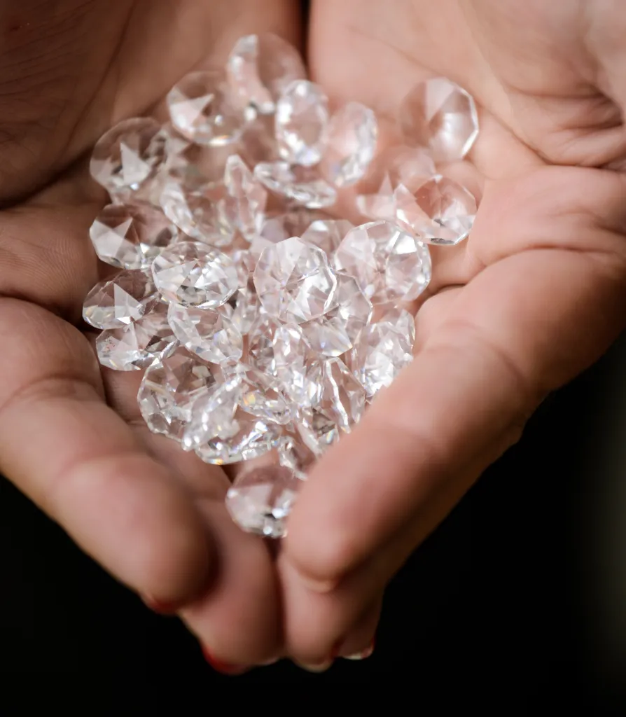 Woman's hands holding a pile of diamonds.